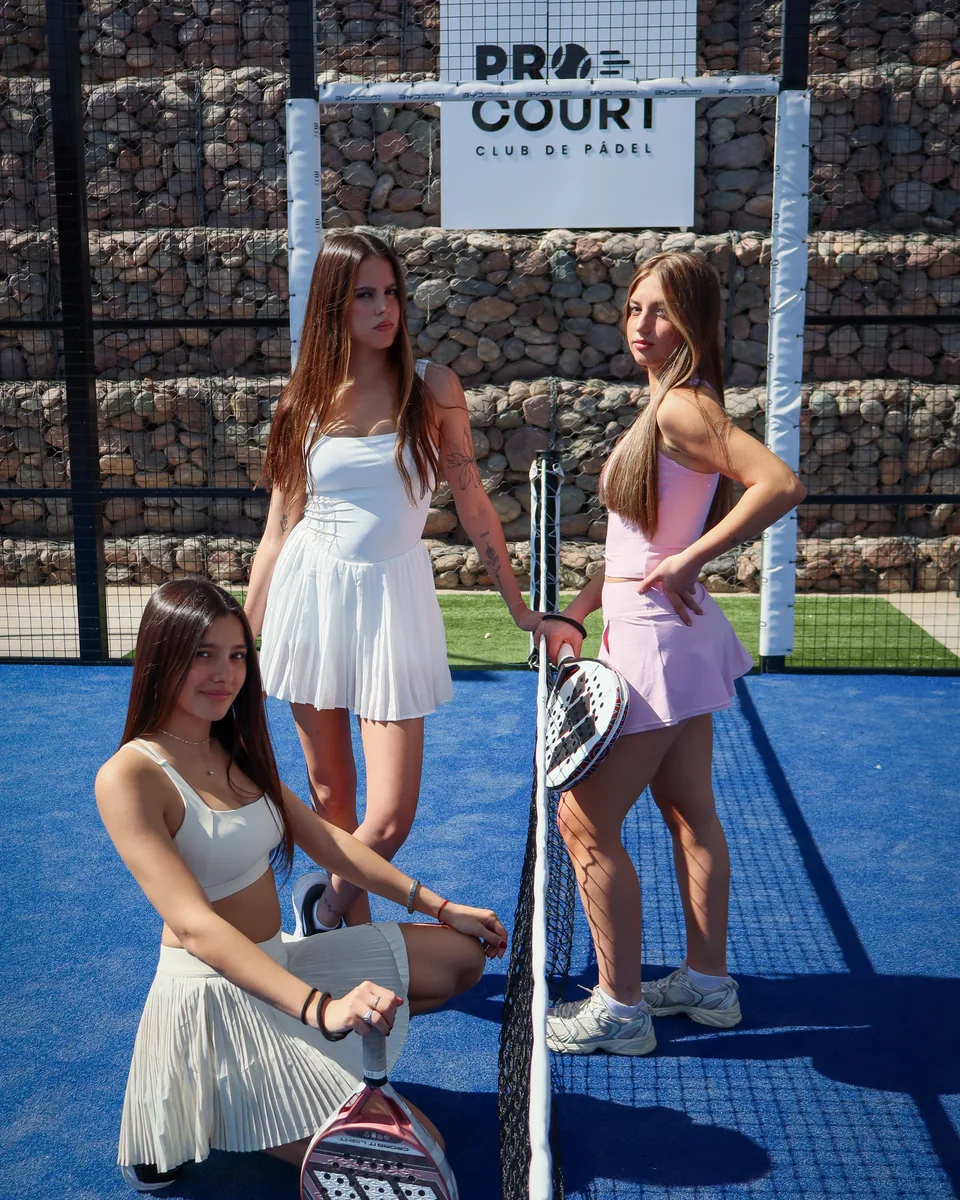 Tres jugadoras posando junto a la red en el club de pádel